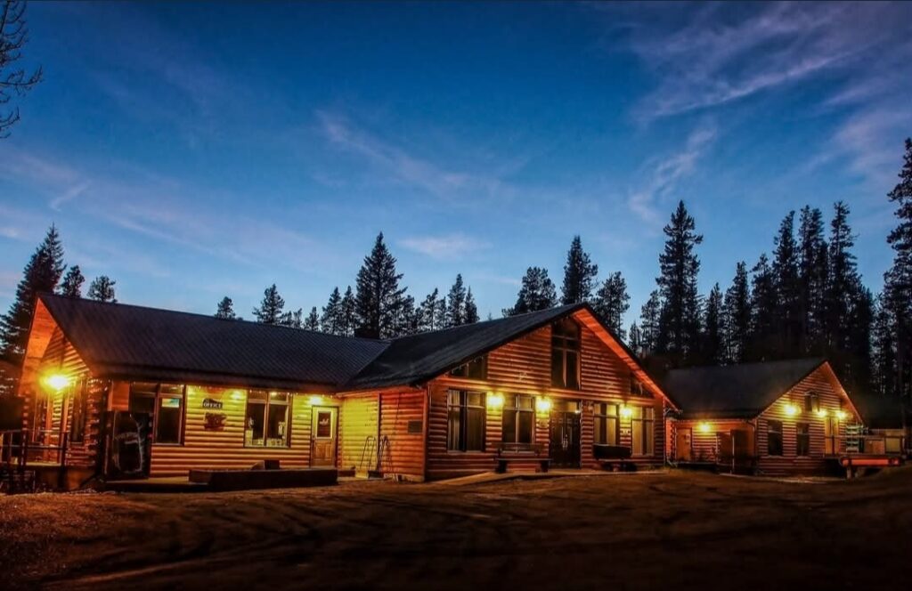 The front of a red-hued cabin. Lanterns glow against the cabin.
